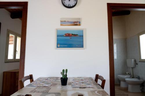 a dining room table with a clock on the wall at B&B L'Uliveto in Marzamemi