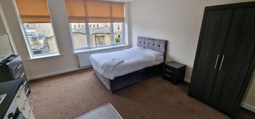 a small bedroom with a bed and two windows at PENTHOUSE APARTMENT IN CENTRAL HALIFAX in Halifax