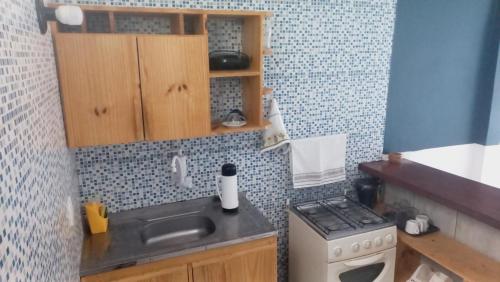 uma pequena cozinha com um lavatório e um fogão em Casa da Lis pé na areia em Morro de São Paulo
