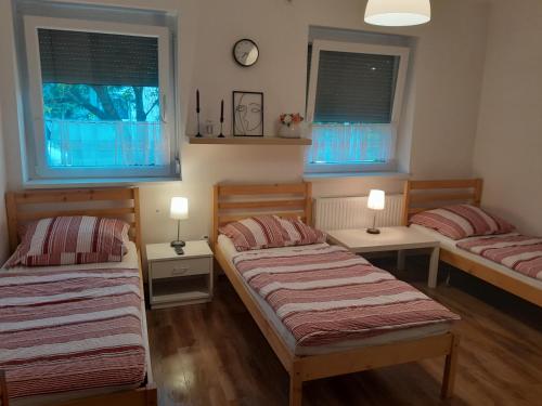 a bedroom with two beds and two windows at Vörösmarty Apartman in Dombóvár