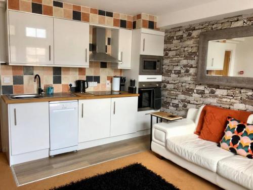 a living room with a white couch and a kitchen at Bank Building Apartments in Barnoldswick
