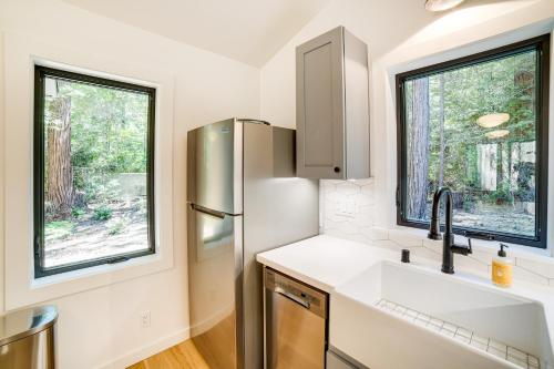 eine Küche mit einem Kühlschrank und 2 Fenstern in der Unterkunft Peaceful Mendocino Cottage Surrounded By Redwoods in Mendocino