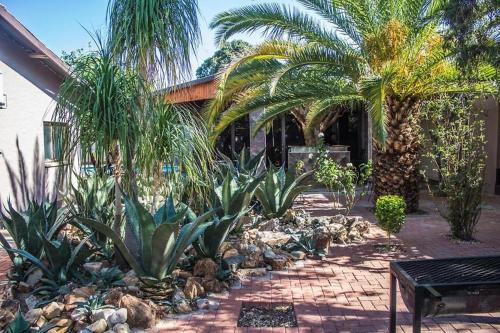 un jardín con palmeras y un banco frente a un edificio en Ethithiya Guesthouse & Conferencing, en Windhoek