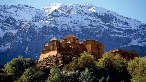 a building on a hill with a snow covered mountain at Imlil in Marrakesh