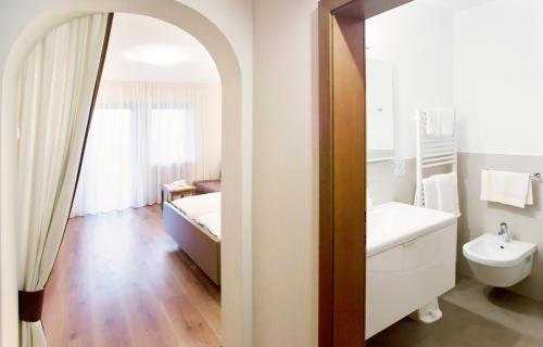 een badkamer met een wastafel, een toilet en een spiegel bij Hotel Walder in Schenna