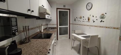 a kitchen with a table and a clock on the wall at Moderno y luminoso 2 dormitorios con todas las comodidades en Pontevedra ciudad in Pontevedra