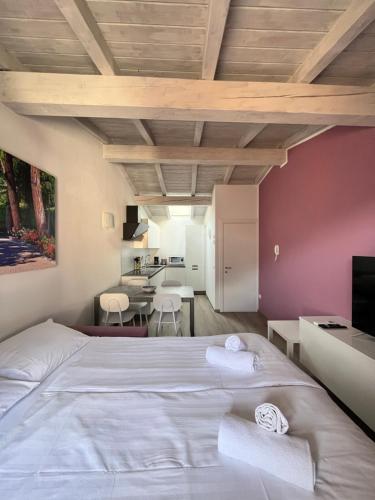 a bedroom with a large white bed and a kitchen at Casa Margheritina in Malcesine