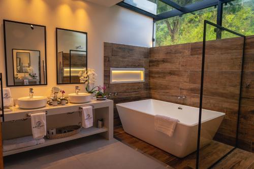 uma casa de banho com 2 lavatórios e uma banheira em Saison Resort & Spa em Itaipava