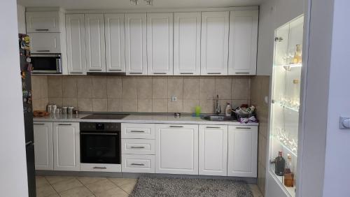 a white kitchen with white cabinets and a sink at Apartman LUX BRUS in Brus