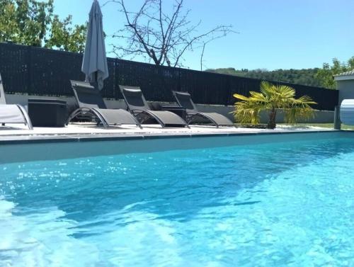 uma piscina com cadeiras e um guarda-sol em CHAMBRE & SDB PRIVÉE avec piscine en bord de Via Rhona em Sarras
