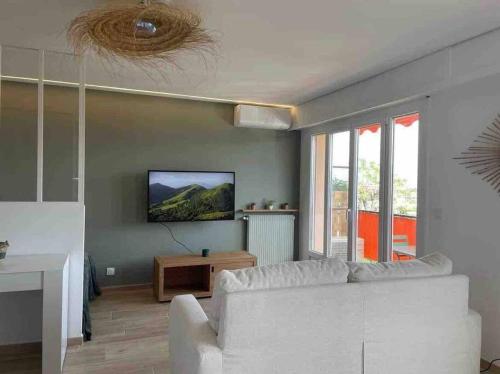 uma sala de estar com um sofá branco e uma televisão em Cocon Méditerranéen em Cagnes-sur-Mer