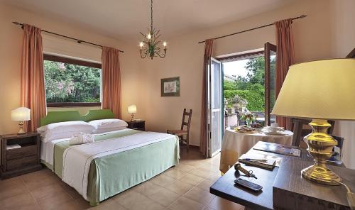 ein Schlafzimmer mit einem Bett und einem Tisch mit einer Lampe in der Unterkunft Hotel Villa Sirina in Taormina