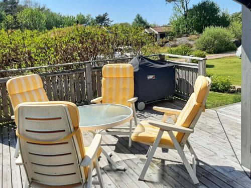 three chairs and a table and a trash can on a deck at 4 person holiday home in GRUNDSUND in Grundsund