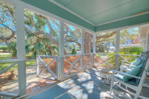 a screened in porch with two chairs and a tree at Hidden Treasure in Oak Island