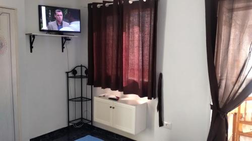 Zimmer mit einem TV, einem Vorhang und einem Fenster in der Unterkunft Apartamentos Doña Carmen in Los Silos