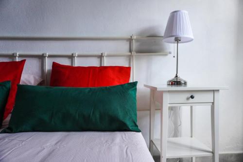 a bed with red and green pillows next to a table at Casa Ángela, Canarian Heritage in Los Silos