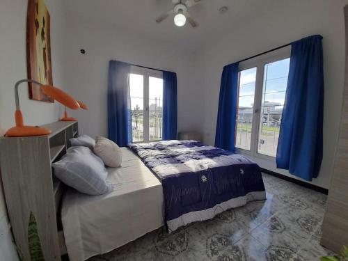 a bedroom with a bed with blue curtains and a window at Hospedaje La Plata 2 in La Plata