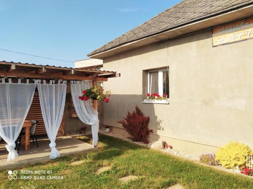 una casa con cortinas blancas en el patio en Chalúpka Anit 