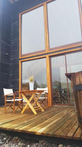 a wooden deck with a table and chairs and windows at CABAÑAS LODGE LOS COIHUES 2 VALLE LAS TRANCAS/TERMAS DE CHILLAN /NEVADOS DE CHILLAN in Pinto