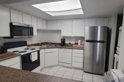 a kitchen with white cabinets and a stainless steel refrigerator at Dream King Bed-2BD-12 min to Strip in Las Vegas