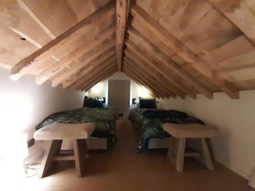 a attic room with two beds and two stools at Le Coq d'or in Theux