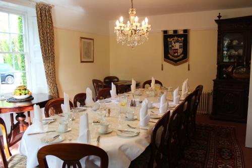 a dining room with a long table with chairs and a chandelier at Molland Manor House Bed & Breakfast in Sandwich