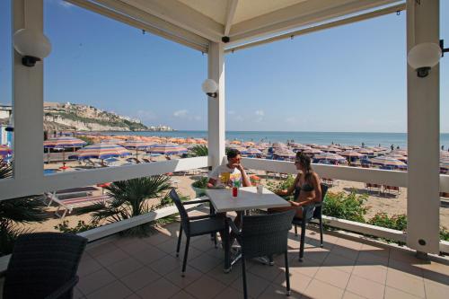 two people sitting at a table on the beach at Bikini Hotel in Vieste