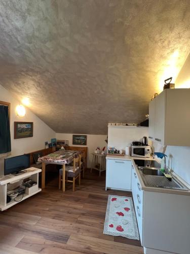 a kitchen with white appliances and a dining room at Piccolo Nido Falcade in Falcade