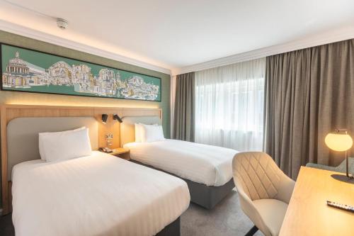 a hotel room with two beds and a chair at Holiday Inn London - Regent's Park by IHG in London