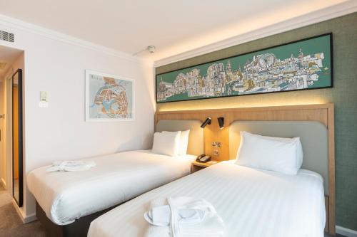 two beds in a hotel room with a picture on the wall at Holiday Inn London - Regent's Park by IHG in London