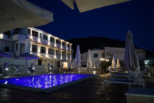 a hotel with a swimming pool at night at Kostas Beach Apartments in Agios Gordios