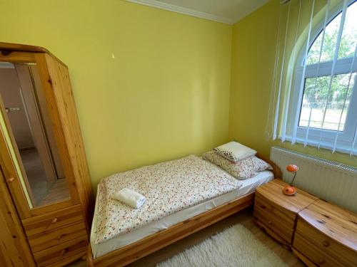 een kleine slaapkamer met een bed en een raam bij Bodzás vendégház - Bodza u.4. in Kiskunmajsa