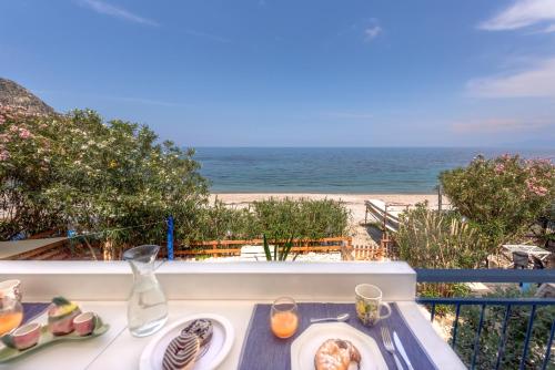 a table with a plate of food and the beach at Dimore di mare - Beachfront Apartments in Santa Flavia