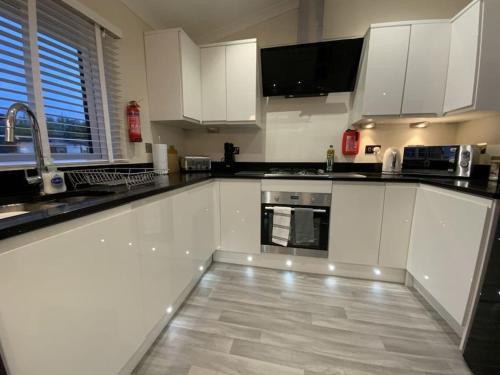 a kitchen with white cabinets and a tile floor at Elora's Dream in Wisbech