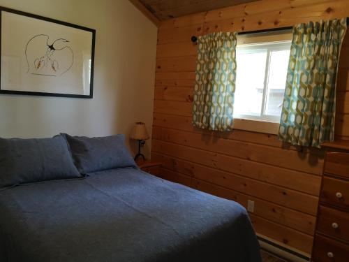 1 dormitorio con cama y ventana en The Pines Cottage Resort, en Oxtongue Lake