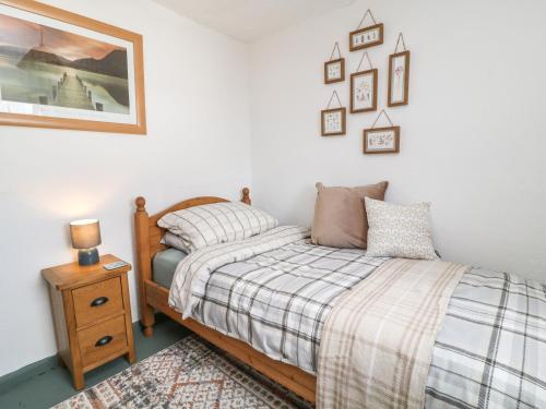 um quarto com uma cama e uma mesa de cabeceira com um candeeiro em CurLi Cottage em Bideford