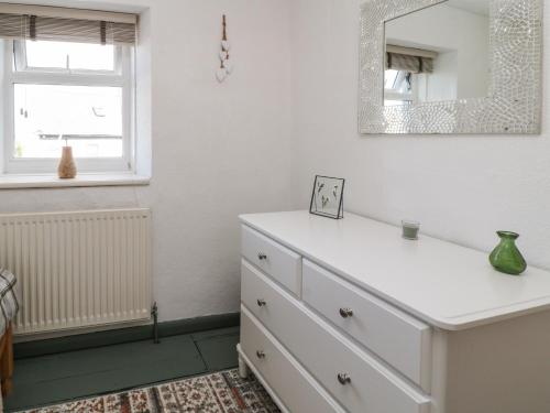 uma cómoda branca num quarto com um espelho em CurLi Cottage em Bideford