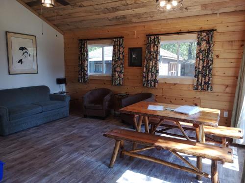 a living room with a table and a couch at The Pines Cottage Resort in Oxtongue Lake