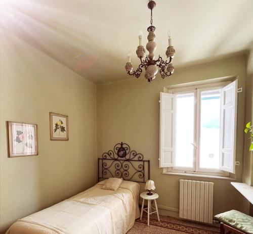 a bedroom with a bed and a window and a chandelier at Bed and Breakfast Evelina in Lucca