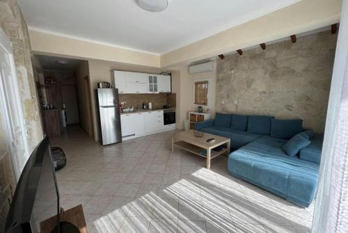 a living room with a blue couch and a kitchen at 2-Стаен Апартамент in Ignatievo
