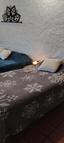 a bed with a blanket with snowflakes on it at Alojamiento Amancay in Trenque Lauquen