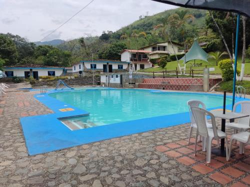 a large swimming pool with a table and chairs at Hosteria Puerta del Nus in Cisneros