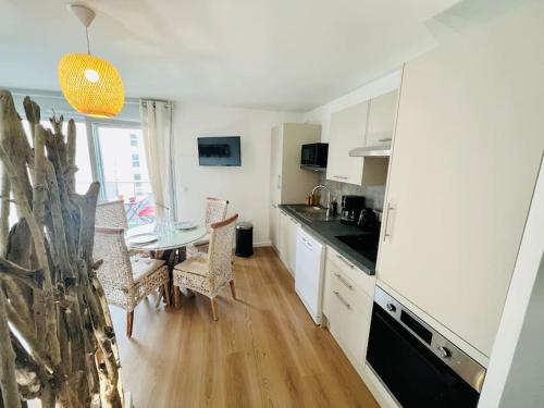 une cuisine avec des armoires blanches et une table avec des chaises dans l'établissement L’Atelier des rêves à 200 m de la plage, à Fort-Mahon-Plage