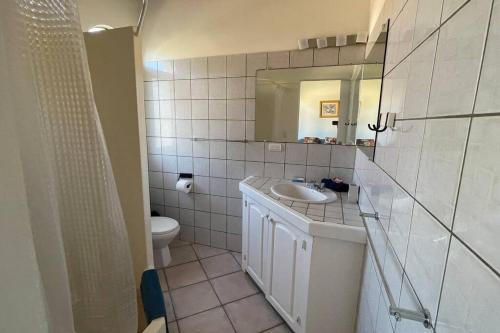 a bathroom with a sink and a toilet and a mirror at Central Cabarete Apartment in Cabarete