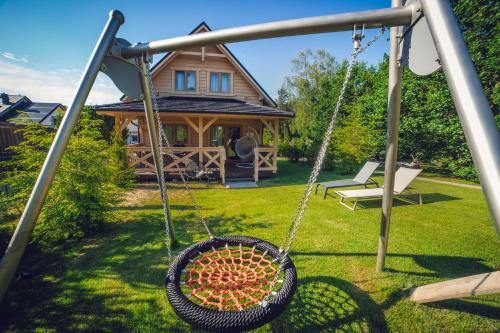 a swing in a yard with a house at SeaUSasino - Luksusowe Drewniane Domy z Kominkami in Sasino