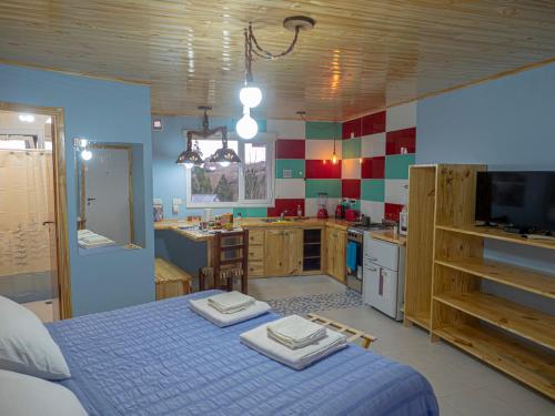 a bedroom with a blue bed and a kitchen at Cabañas La Lila in Huinganco