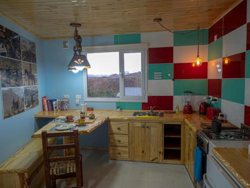 a kitchen with red white and green tiles on the walls at Cabañas La Lila in Huinganco
