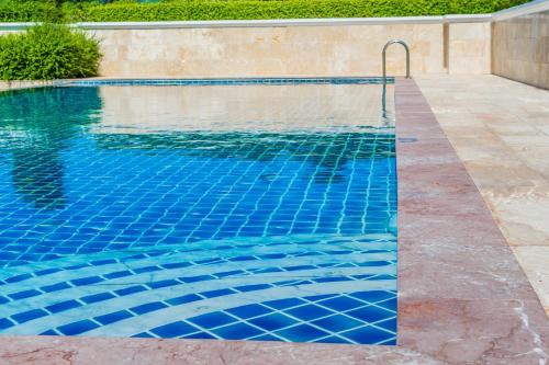 a swimming pool with blue tiles on the floor and a swimming pool at Holiday Inn Express & Suites - Austin - Manor by IHG in Manor