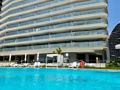 a hotel with a swimming pool in front of a building at Luxury apartment with stunning sea views in Sunset Cliff Benidorm in Benidorm