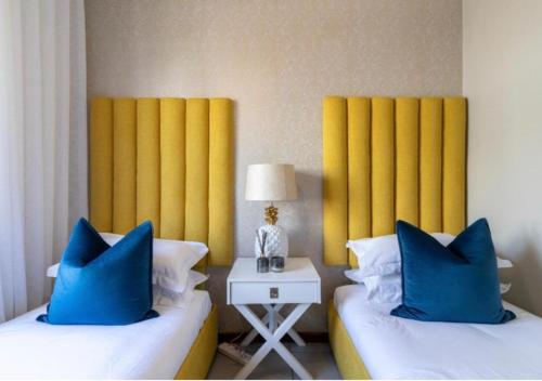 duas camas com almofadas azuis num quarto de hotel em The Steynview Apartment - Fourways Sandton em Joanesburgo